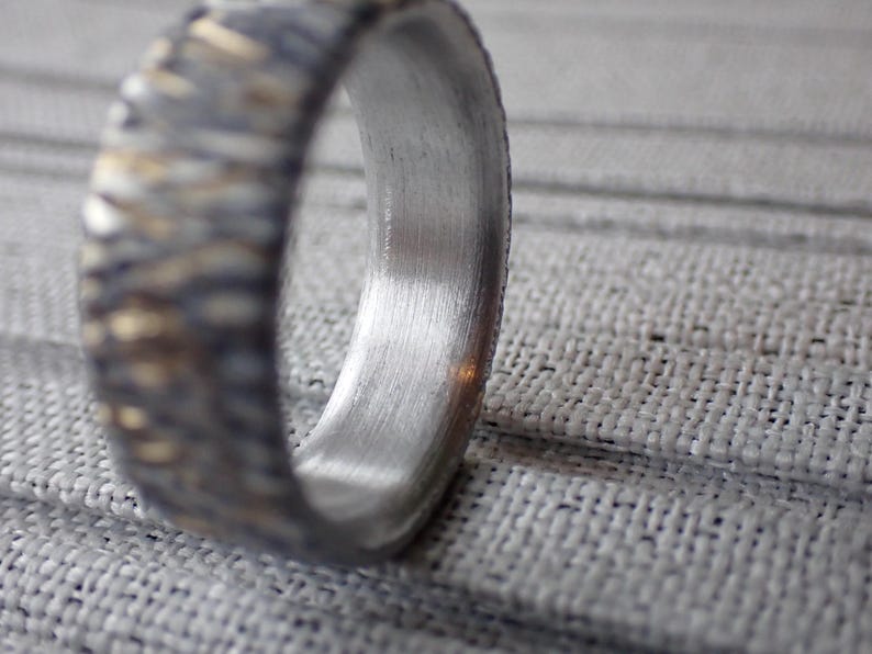 May include: A silver ring with a textured band and a smooth, polished inner surface.