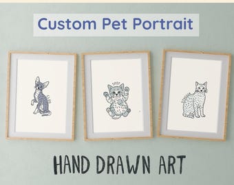 Op de afbeelding: Drie ingelijste illustraties van katten, elk met een andere pose en naam. De lijsten zijn van lichtbruin hout en de illustraties zijn met de hand getekend in zwart-wit met grijze schaduwen. De tekst "Custom Pet Portrait" staat bovenaan de afbeelding en "HAND DRAWN ART" onderaan.