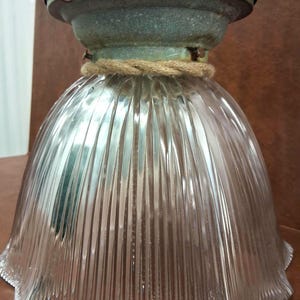 May include: Vintage-style glass pendant light fixture. The clear glass shade has vertical ridges and a scalloped edge. The fixture includes a metal top with a rope accent. The metal top has a distressed, aged appearance.