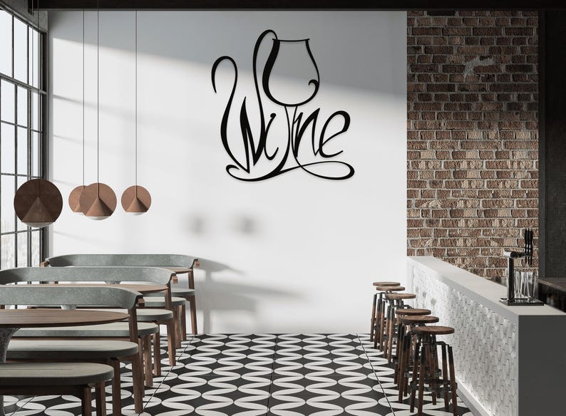 May include: Black metal wall art spelling "Wine" with a wine glass design. The art is mounted on a white wall in a bar or restaurant setting. The room features a black and white checkered floor, wooden tables, and bar stools.
