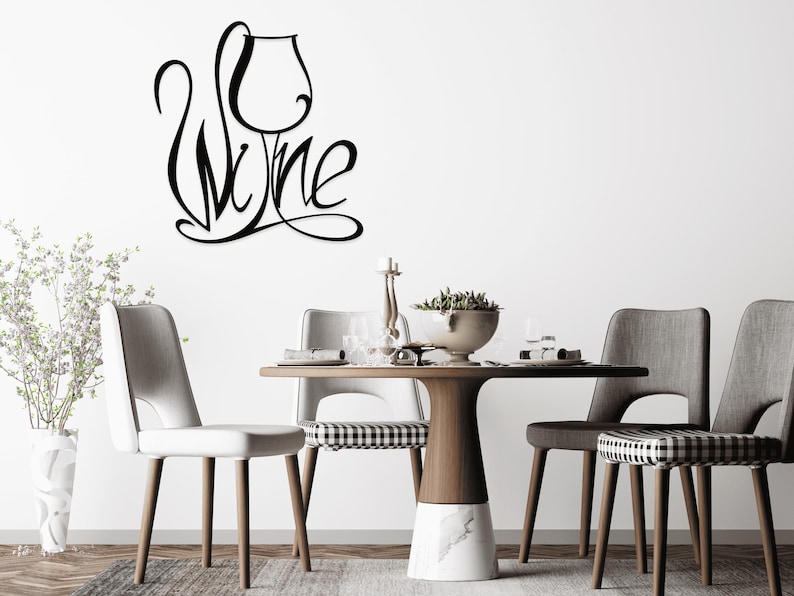 May include: Black metal wall art spelling "Wine" with a wine glass design. The art is mounted on a white wall above a table set for dining. The table has a wooden top and a marble base, surrounded by chairs.