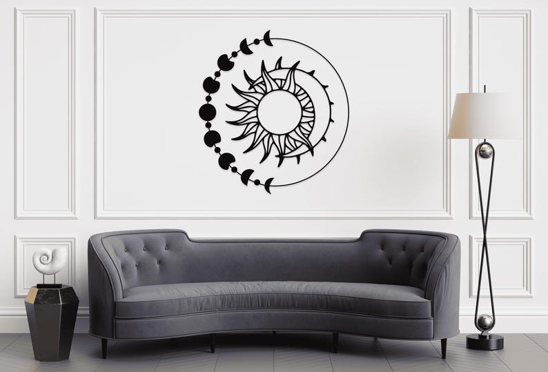 May include: Black wall art featuring a sun with radiating lines, a crescent moon, and a series of connected circles and crescent moons. The artwork is mounted on a white wall above a gray sofa.