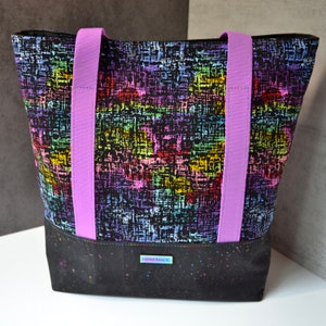 May include: A black tote bag with purple straps and a colorful abstract pattern. The bag has a black bottom with white speckles and a "HANDMADE" label.