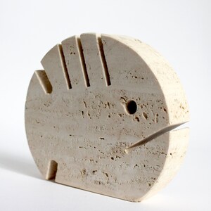 K&ouml;nnte beinhalten: Eine beige Steinskulptur eines Fisches mit einem geschnitzten Mund und Auge. Die Skulptur ist aus Travertin und hat eine raue, strukturierte Oberfl&auml;che.