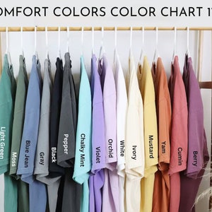 Puede incluir: Carta de colores que muestra 14 colores diferentes de camisetas, incluyendo verde claro, azul vaquero, gris, negro, pimienta, menta cremosa, violeta, orqu&iacute;dea, blanco, marfil, mostaza, &ntilde;ame, comino y baya.