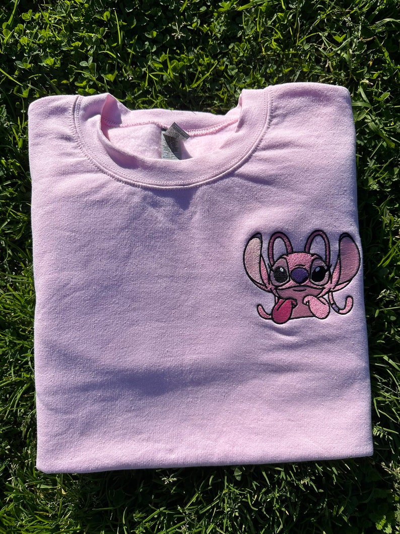 Puede incluir: Sudadera rosa con una peque&ntilde;a imagen bordada de Stitch de Lilo & Stitch. Stitch lleva gafas y saca la lengua.