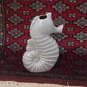 May include: A white ceramic seahorse figurine with a textured surface. The figurine is a vase with an opening at the top for flowers.