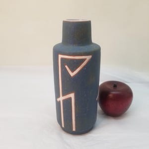 May include: A blue ceramic vase with white geometric designs. The vase has a textured surface and a rounded bottom.