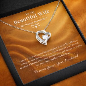 Op de afbeelding: Een zilveren hartvormige hangerketting met een centrale heldere edelsteen, gepresenteerd in een zwarte geschenkdoos. De doos bevat de tekst "To My Beautiful Wife" en een bericht van "Your Husband."