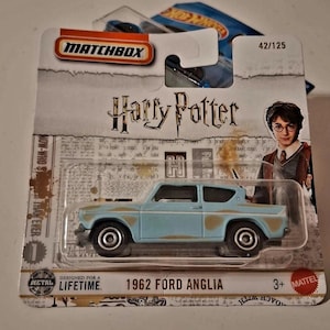Könnte beinhalten: Matchbox-Modellauto des 1962 Ford Anglia, hellblau mit rostfarbenen Akzenten, aus der Harry Potter-Serie. Die Verpackung enthält das Harry Potter-Logo und ein Bild von Harry Potter. Entworfen für ein Leben lang.