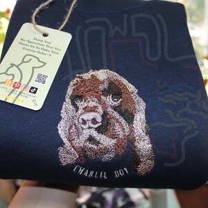Puede incluir: Una sudadera azul marino con una imagen bordada de un perro marr&oacute;n y blanco. El nombre del perro, "CHARLIE BOY", est&aacute; bordado debajo de la imagen.