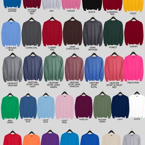 May include: A collection of 25 different colored crew neck sweatshirts, each with a hanger. The sweatshirts are arranged in five rows of five, with each row representing a different color family. The colors include antique sapphire, antique cherry red, ash, azalea, black, cardinal red, gold, carolina blue, charcoal, cherry red, dark chocolate, dark heather, forest, garnet, graphite heather, heather sport dark navy, heather sport dark green, heather sport dark maroon, heather sport royal, heather sport scarlet red, heliconia, irish green, indigo blue, light blue, light pink, maroon, military green, navy, white, red, orange, purple, sapphire, royal, sand, and sport grey.