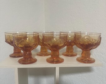 May include: Set of six amber glass dessert dishes with a diamond pattern. The dishes have a footed base and are perfect for serving ice cream, pudding, or other desserts.