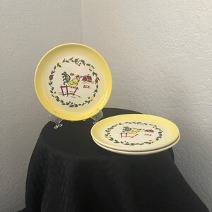 May include: Three yellow ceramic plates with a rooster design. The plates have a green and red border with a white center. The rooster is yellow with a red comb and wattle.