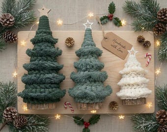 May include: Three macrame Christmas trees in dark green, sage green, and cream, each featuring a tiered fringe design, a wooden base, and a star topper. A brown paper tag with the handwritten text Handmade with Love is attached to the set.