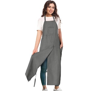 May include: A gray apron with a bib, pocket, and side pockets. The apron has a split front design and is made of a durable fabric. The apron is designed for kitchen or workshop use.