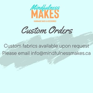 May include: A light blue background with a white brushstroke design. The text "Mindfulness MAKES" is in orange and teal. The text "Handmade Bags & Accessories" is in black. The text "Custom Orders" is in black. The text "Custom fabrics available upon request" is in black. The text "Please email info@mindfulnessmakes.ca" is in black.