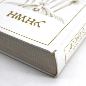 May include: A white book with gold lettering and accents. The title includes the text "Les Cl&eacute;s D'Enoch" and "HMHK". The book's pages are visible, and the cover has a gold border.