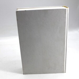 May include: A hardcover book with a light gray cover and white pages. The spine is white, and the top corner has a gold accent. The book is standing upright on a white surface.