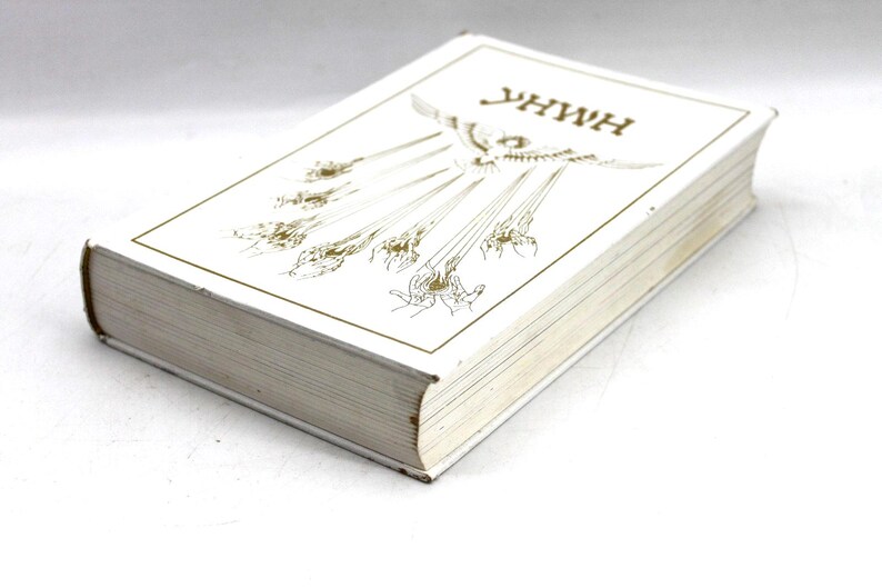 May include: A hardcover book with a white cover and gold lettering and illustrations. The title "YHWH" is at the top. The book's pages are visible, and the edges are slightly worn.