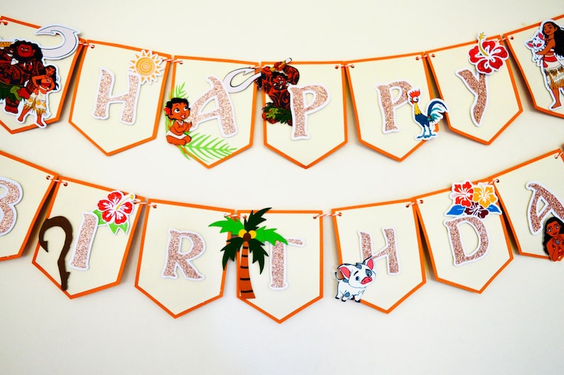 May include: A pink and orange banner with the words "Happy Birthday" in white letters with glitter. The banner has various characters from the movie Moana, including Maui, Pua, and Hei Hei.