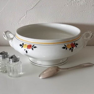 May include: White ceramic serving bowl with handles, decorated with a yellow band and fruit motifs. Includes two glass salt shakers with metal lids and a silver spoon. A vintage kitchenware set.
