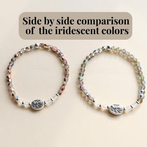 May include: Two beaded bracelets with iridescent colors are displayed side by side. Each bracelet features a central oval charm and is composed of small, faceted beads in shades of silver, pink, and clear. The text "Side by side comparison of the iridescent colors" is at the top.