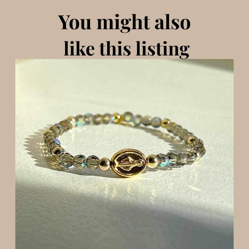 May include: A beaded stretch bracelet with a gold-colored centerpiece and beads. The bracelet features a gold-colored oval centerpiece with an engraved design. The beads are a mix of clear and iridescent, with gold-colored accent beads.