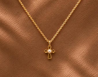 May include: A gold chain necklace featuring a small cross pendant. The cross has a polished gold finish with four flared arms and a single, small, round white pearl set in the center where the arms of the cross intersect.
