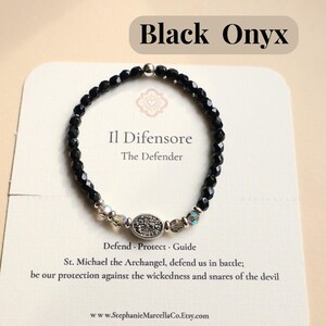 May include: Black Onyx bracelet with faceted black beads, clear and iridescent accent beads, and a silver-toned centerpiece. The card behind the bracelet reads "Il Difensore, The Defender."