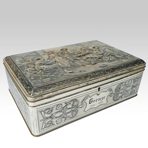 Può includere: Una scatola di metallo rettangolare con coperchio incernierato. Il coperchio presenta una scena in rilievo dettagliata di figure in abiti d'epoca. La scatola ha volute decorative e la parola "Grenze" con le date 1725-1805.