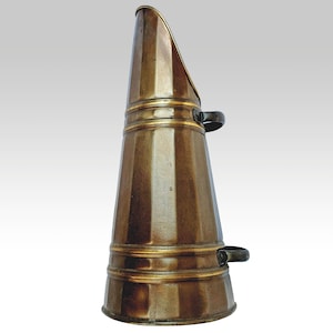 Può includere: Un secchio per carbone in ottone con due manici. Il secchio ha una forma conica con una bordatura dorata intorno alla parte superiore e inferiore.