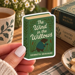 May include: A die-cut sticker featuring a green book cover illustration of The Wind in the Willows by Kenneth Grahame. The design shows a mole character wearing a blue coat and holding a walking stick, surrounded by tall grass and cattails.