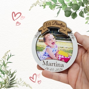 Peut inclure: Un cadre photo rond en bois blanc avec une photo d'une petite fille. Le cadre porte une bannière avec l'inscription "Mi Bautizo" et le nom "Martina" avec la date "26-05-2026". Le cadre est orné d'éléments floraux.