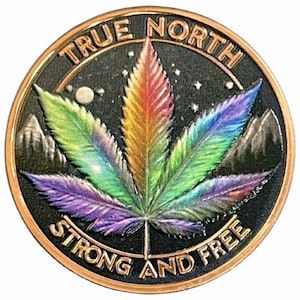 May include: A circular, bronze-toned coin featuring a vibrant cannabis leaf, transitioning from purple to green to orange. The coin is inscribed with "TRUE NORTH" and "STRONG AND FREE". Mountains and stars are in the background.