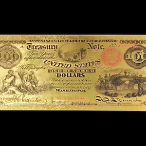 May include: A gold-coloured United States Treasury Note for 100 dollars. The note features detailed engravings, including the text "United States" and "One Hundred Dollars." The design includes images of people and buildings, with the number "100" prominently displayed.