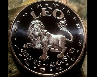 Peut inclure: Une pièce d'argent avec un fond noir représentant le signe astrologique du Lion. La pièce porte les dates du 23 juillet au 21 août et le mot "LEO" en grandes lettres.