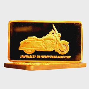 Può includere: Un oggetto rettangolare color oro con un rilievo dettagliato di una motocicletta. La motocicletta è una Harley-Davidson Road King FLHR, con la scritta "2019 HARLEY-DAVIDSON ROAD KING FLHR" sottostante.
