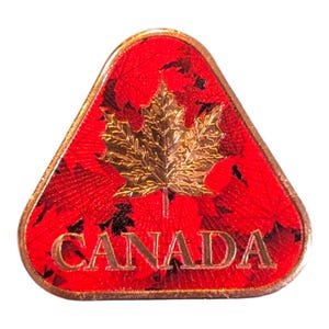 May include: A triangular pin with a gold maple leaf design on a red background, with the word "CANADA" in gold. The pin has a gold border and is a symbol of Canadian identity.
