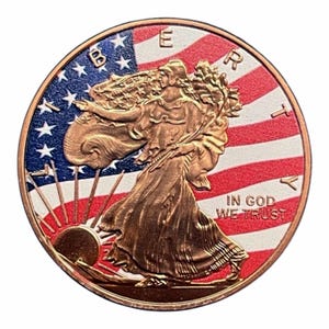 May include: A circular, copper-coloured coin depicting Lady Liberty walking, set against the American flag. The coin is inscribed with the words "LIBERTY" and "IN GOD WE TRUST".