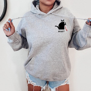 May include: Gray hooded sweatshirt with a black cat holding a knife and the text "WHAT?" printed on the front.