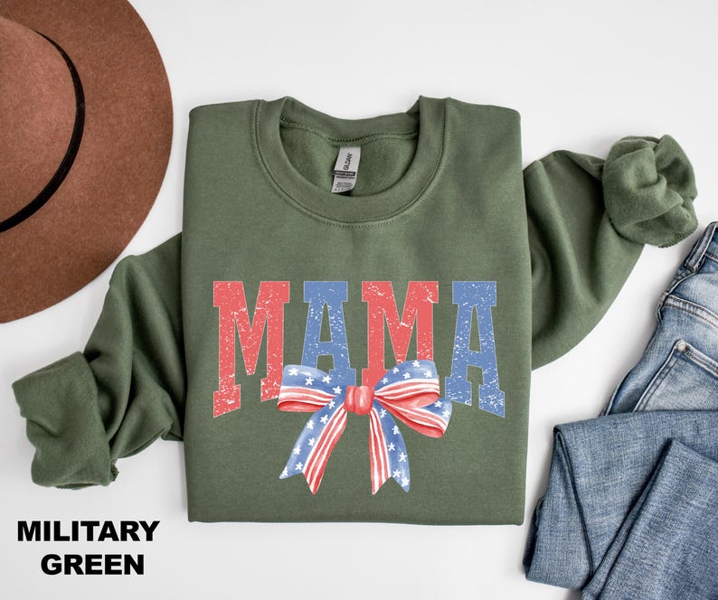 Pu&ograve; includere: Una felpa verde militare con la parola "MAMA" in lettere rosse, bianche e blu. Un fiocco rosso, bianco e blu con stelle &egrave; centrato sotto la parola "MAMA".