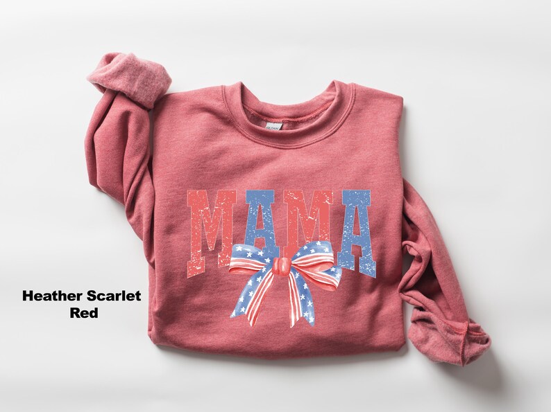 Pu&ograve; includere: Una felpa di colore rosso scarlatto melange con la parola "MAMA" stampata in rosso, bianco e blu con un fiocco rosso, bianco e blu.