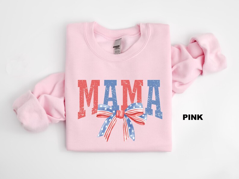 Pu&ograve; includere: Felpa rosa con la parola "MAMA" in lettere rosso, bianco e blu con un fiocco rosso, bianco e blu con stelle.