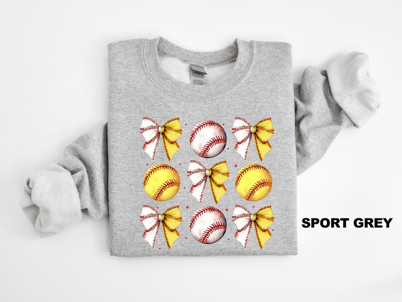 May include: A grey sweatshirt with a design of yellow and white softball bows and baseballs. The text "SPORT GREY" is in the bottom right corner of the image.