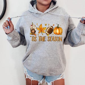 May include: Gray hooded sweatshirt with a graphic of a coffee cup, a football, and a pumpkin with the text "'Tis the season".