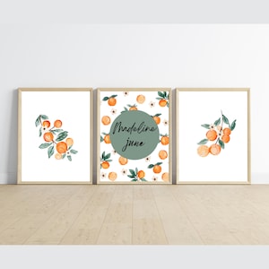 May include: Three framed prints with a watercolor design of orange blossoms and fruit. The middle print has a green circle with the text "Madeline June" in black.