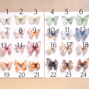 May include: A collection of twenty-four individual butterfly stickers arranged on two white sheets, numbered 1 through 24. Each butterfly features distinct colour patterns, including shades of blue, pink, orange, yellow, green, and black.
