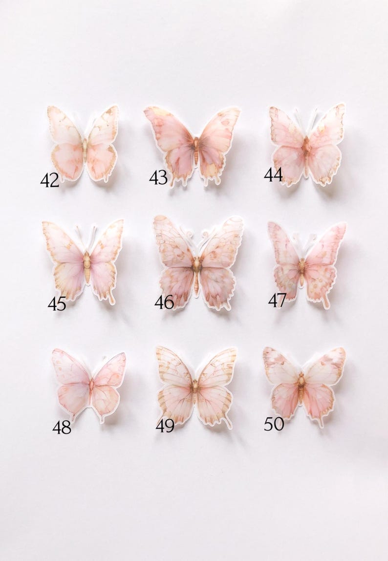 May include: A collection of nine individual butterfly stickers arranged in a grid, each featuring soft watercolour-style pink and peach tones. Each butterfly is labelled with a unique black number from 42 to 50, showcasing distinct wing patterns.