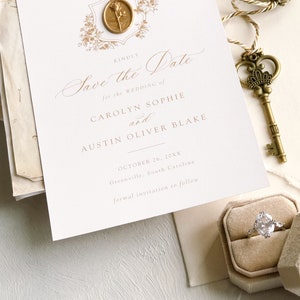 K&ouml;nnte beinhalten: Save the Date Hochzeitskarte mit einem goldenen Siegel aus Wachs und floralem Design. Die Einladung ist f&uuml;r Carolyn Sophie und Austin Oliver Blake, die Hochzeit findet am 26. Oktober 20XX in Greenville, South Carolina statt.